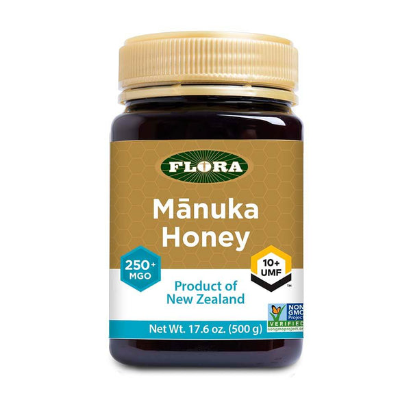 A jar of Flora Mānuka Honey with labels indicating UMF 10+ and MGO 261+, certified by the Unique Mānuka Factor Honey Association, sourced from New Zealand.