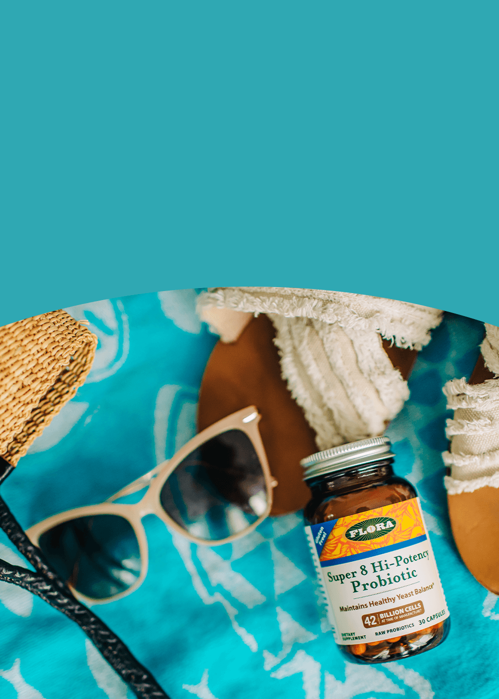 Flora probiotic bottle on a blue towel with sunglasses and a hat