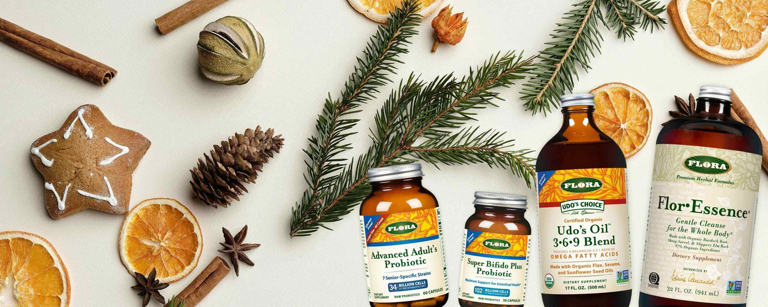 Flora supplement bottles on a festive background with oranges, cinnamon, and pine branches.
