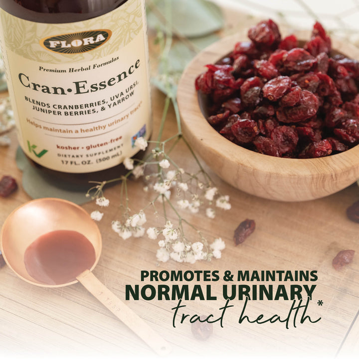 Cran Essence urinary tract supplement liquid in copper spoon and 17 oz liquid supplement container, pictured with dried cranberries and hawthorn